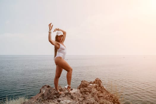 Woman travel sea. Young Happy woman in a long red dress posing on a beach near the sea on background of volcanic rocks, like in Iceland, sharing travel adventure journey