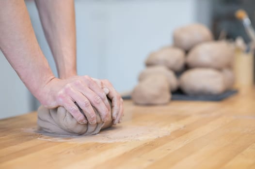 A potter kneads clay before using it in the workshop. Close-up of a man's hands