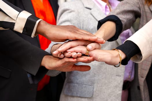 Five happy multiethnic women stacking hands in the city