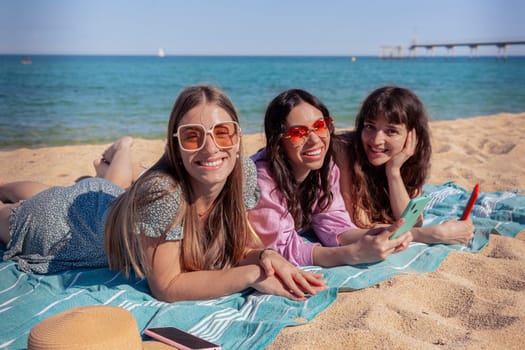 Group of smiling multiethnic women enjoying vacation. Beautiful and cheerful girls of generation z pose for a photo with a mobile phone.