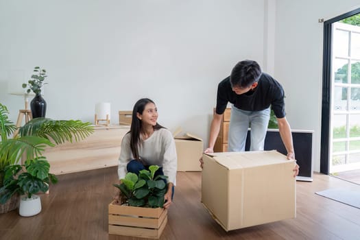 A young couple is seen moving into their new house, unpacking boxes, and arranging plants in a bright, modern living room.