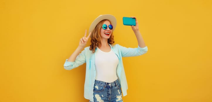 Joyful happy young woman laughs taking selfie with phone, modern cheerful girl in summer tourist straw hat on yellow background