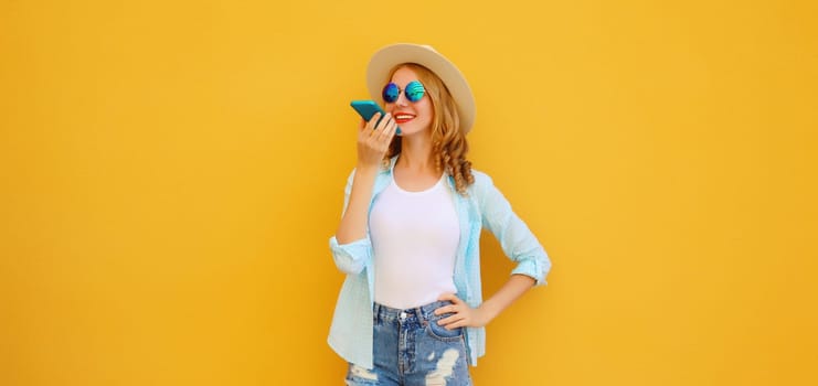 Happy young woman holding talking on the phone, using voice command recorder, assistant or takes calling on smartphone in casual clothing on bright yellow background