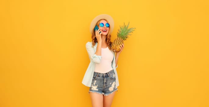 Summer vacation, happy joyful woman calling on phone with pineapple fruit in tourist hat, cheerful girl talking on the smartphone on yellow studio background