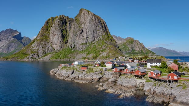 Hamnoy fishing village on Lofoten Islands, Norway with red rorbu houses, A picturesque village nestled amongst dramatic mountains and a serene fjord in the Lofoten Islands, Norway.