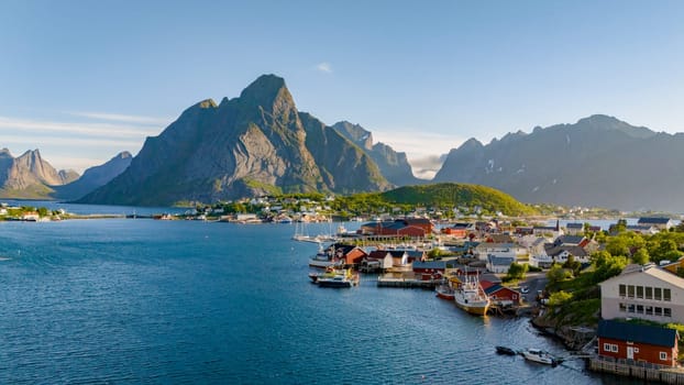 A picturesque view of a charming Norwegian coastal village, surrounded by majestic mountains and a tranquil blue sea. Reine, Lofoten, Norway