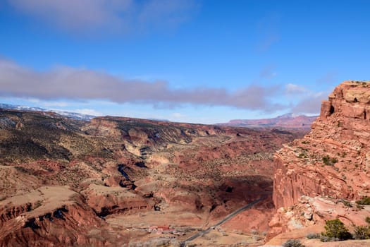 Stunning aerial view of Capitol Reef National Park in Utah, showcasing expansive red rock formations, rugged terrain, and a bright blue sky - Fruita District, USA