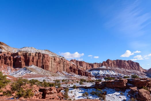 Stunning snow-covered red rock formations under a clear blue sky in Capitol Reef National Park, Utah. Winter scenery showcases the park's geological features and breathtaking natural beauty - USA