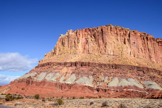 Breathtaking landscape shot of Waterpocket Fold geological rock layers in Capitol Reef National Park, Utah. Features rugged rock formations and vibrant colors under a clear blue sky - USA