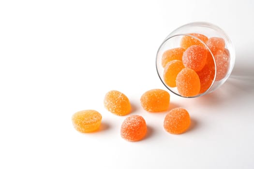 Pieces of apricot marmalade poured from a glass bowl on a white table..