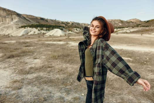 Woman in plaid shirt standing with arms outstretched in the vast field under the open sky