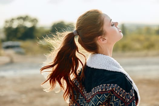 Tranquil woman with flowing hair standing in meadow gazes towards the heavens with serene eyes shut