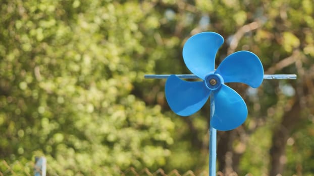 A blue vane weathervane spins in the wind in the summer