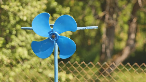 A blue vane weathervane spins in the wind in the summer