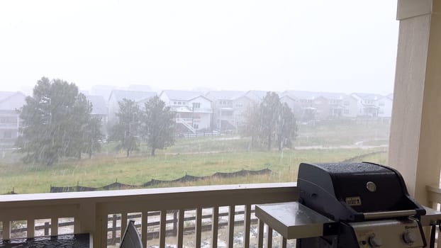 Castle Rock, Colorado, USA-June 12, 2024-Slow motion-Image capturing a hail storm on a wooden deck, highlighting the impact of hail on patio furniture and the deck surface. Hailstones are visible scattered across the wet deck, with patio furniture in the background.