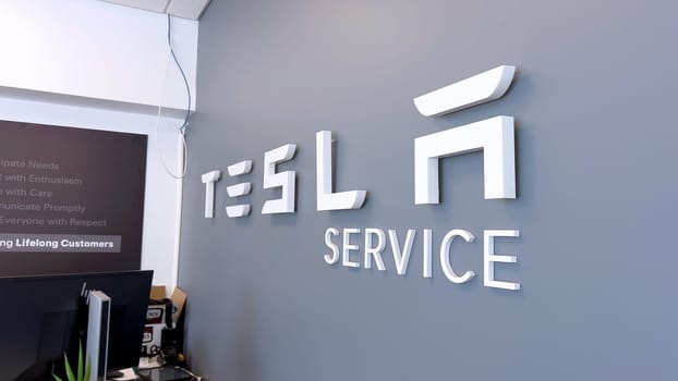 Colorado Springs, Colorado, USA-June 12, 2024-Slow motion-Image of the Tesla Service Center sign on a gray wall, indicating the location for Tesla vehicle maintenance and repairs. The sleek and modern design reflects the company innovative branding.