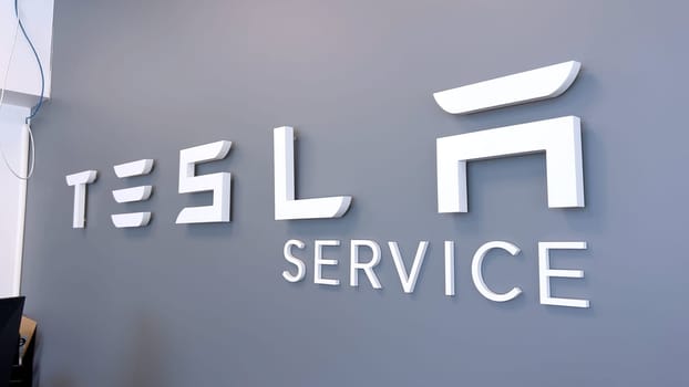 Colorado Springs, Colorado, USA-June 12, 2024-Slow motion-Image of the Tesla Service Center sign on a gray wall, indicating the location for Tesla vehicle maintenance and repairs. The sleek and modern design reflects the company innovative branding.