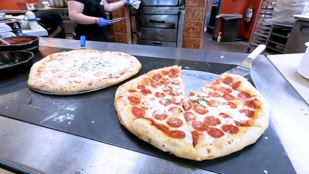 Colorado Springs, Colorado, USA-June 12, 2024-Slow motion-Close-up of a freshly baked pizza slice on a paper plate, placed on a black tray in a pizzeria. The background shows more pizzas being prepared, creating a warm and inviting atmosphere.