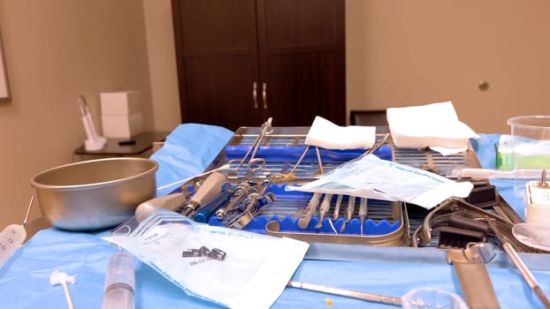 Denver, Colorado, USA-June 10, 2024-Slow motion-A table set with various sterilized surgical instruments, ready for a medical implant procedure. The organized setup includes forceps, scalpels, gauze, and syringes, emphasizing the precision and cleanliness required for implant surgery.