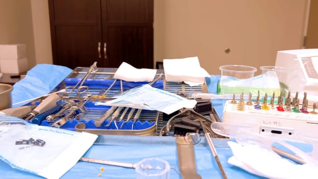 Denver, Colorado, USA-June 10, 2024-Slow motion-A table set with various sterilized surgical instruments, ready for a medical implant procedure. The organized setup includes forceps, scalpels, gauze, and syringes, emphasizing the precision and cleanliness required for implant surgery.