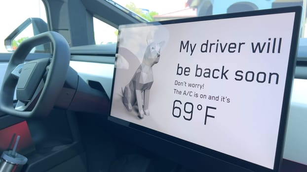 Denver, Colorado, USA-June 11, 2024-Slow motion-The interior of a Tesla car featuring the Dog Mode screen. The display reassures passersby that the driver will be back soon and the air conditioning is set to 69F for the comfort of a pet inside.