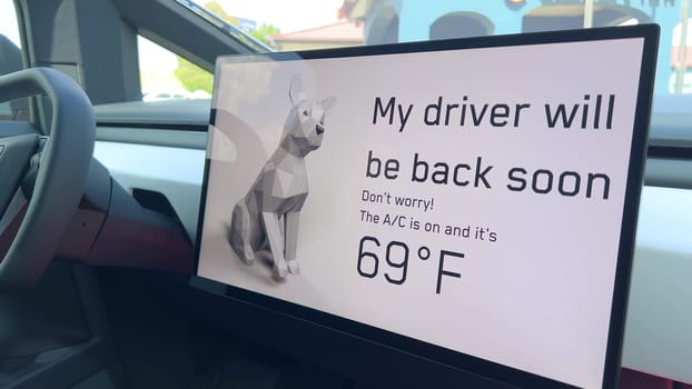 Denver, Colorado, USA-June 11, 2024-Slow motion-The interior of a Tesla car featuring the Dog Mode screen. The display reassures passersby that the driver will be back soon and the air conditioning is set to 69F for the comfort of a pet inside.