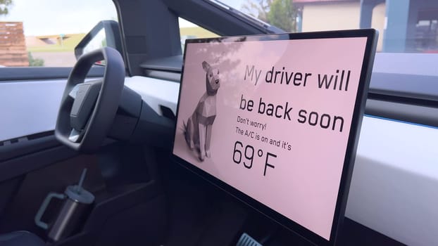 Denver, Colorado, USA-June 11, 2024-Slow motion-The interior of a Tesla car featuring the Dog Mode screen. The display reassures passersby that the driver will be back soon and the air conditioning is set to 69F for the comfort of a pet inside.