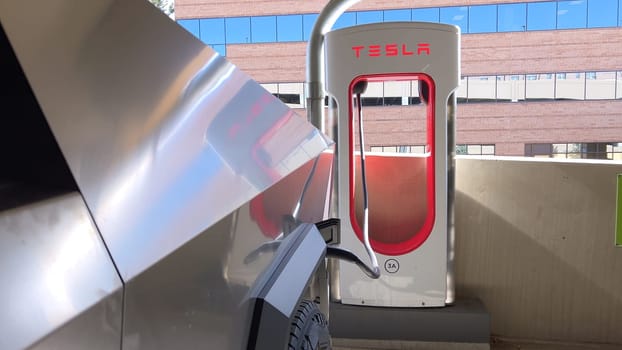 Pueblo, Colorado, USA-June 10, 2024-Slow motion-A Tesla Cybertruck is parked and charging at a Tesla Supercharger station in an underground parking garage. The futuristic design of the Cybertruck stands out against the industrial background.