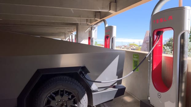 Pueblo, Colorado, USA-June 10, 2024-Slow motion-A Tesla Cybertruck is parked and charging at a Tesla Supercharger station in an underground parking garage. The futuristic design of the Cybertruck stands out against the industrial background.