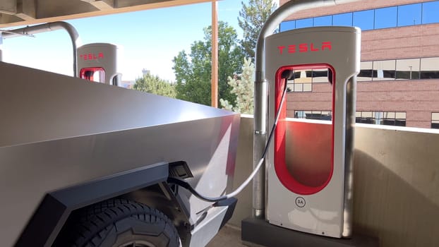 Pueblo, Colorado, USA-June 10, 2024-Slow motion-A Tesla Cybertruck is parked and charging at a Tesla Supercharger station in an underground parking garage. The futuristic design of the Cybertruck stands out against the industrial background.