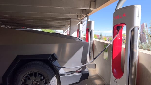 Pueblo, Colorado, USA-June 10, 2024-Slow motion-A Tesla Cybertruck is parked and charging at a Tesla Supercharger station in an underground parking garage. The futuristic design of the Cybertruck stands out against the industrial background.