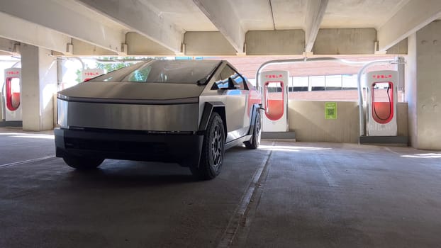 Pueblo, Colorado, USA-June 10, 2024-Slow motion-A Tesla Cybertruck is parked and charging at a Tesla Supercharger station in an underground parking garage. The futuristic design of the Cybertruck stands out against the industrial background.