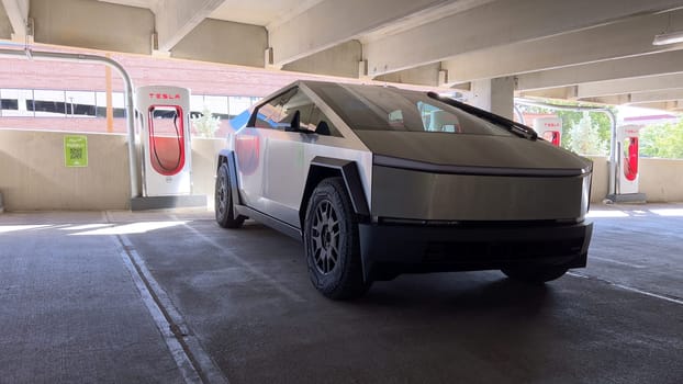 Pueblo, Colorado, USA-June 10, 2024-Slow motion-A Tesla Cybertruck is parked and charging at a Tesla Supercharger station in an underground parking garage. The futuristic design of the Cybertruck stands out against the industrial background.