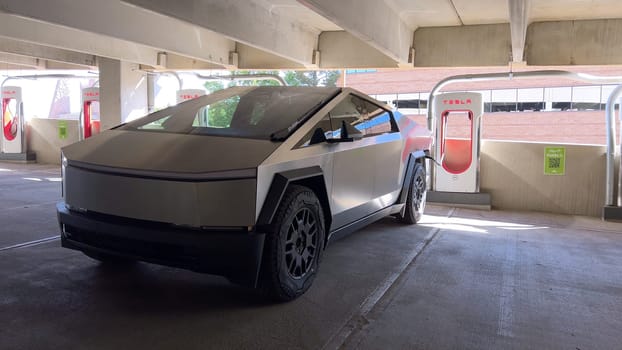 Pueblo, Colorado, USA-June 10, 2024-Slow motion-A Tesla Cybertruck is parked and charging at a Tesla Supercharger station in an underground parking garage. The futuristic design of the Cybertruck stands out against the industrial background.