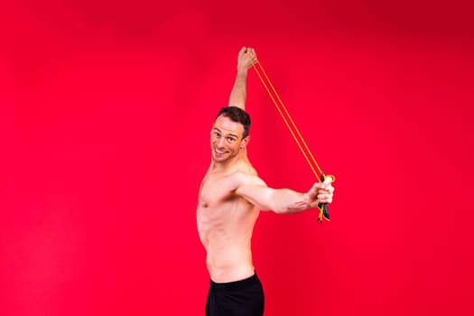 Full length portrait of a young man exercising with a skipping rope and looking at camera