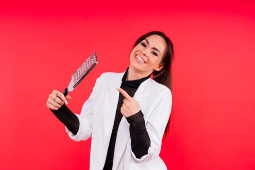 Smiling woman holding a grater on red studio background