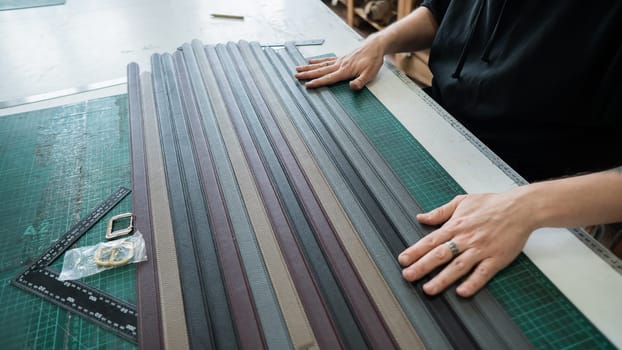 A tanner makes leather belts in a workshop. Close-up of a man's hands