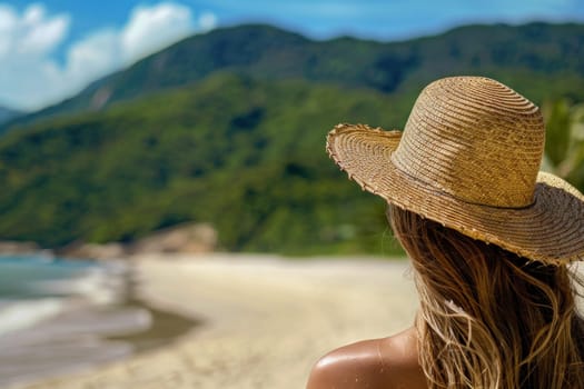 Woman in straw hat enjoying breathtaking view of ocean and mountains on beach vacation travel