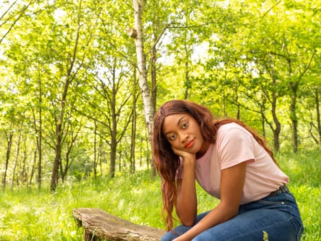 A woman is seated comfortably on a log, surrounded by lush green grass.