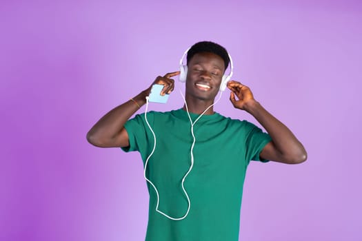 A man wearing headphones and a green shirt listening to music.