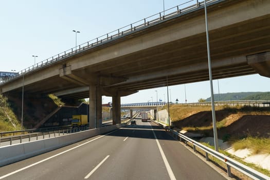 Barcelona, Spain - May 15, 2023: A view of a highway stretching into the distance with a bridge spanning a river in the background under a clear blue sky.