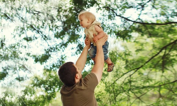 Happy father and son, joyful dad playing with child, holding on hands in summer park