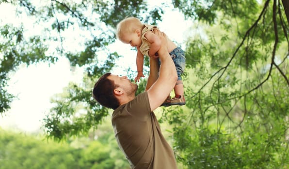 Happy father and son, joyful dad playing with child, holding on hands in summer park