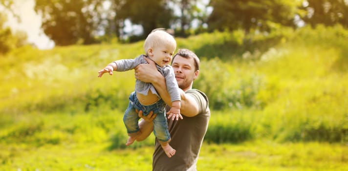 Happy father and son, joyful dad playing with child, holding on hands in summer park