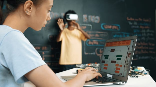 Closeup of school girl hand coding program while african student using VR interact with metaworld. Smart boy wearing virtual reality glasses and playing video games at innovative class. Edification.