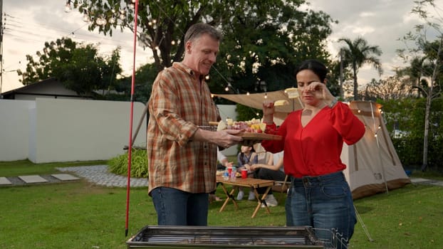 Family all together camp in garden, Old couple grill food for family member. Outdoor camping activity to relax with tasty meal and spend time with young generation cross generation gap. Divergence.