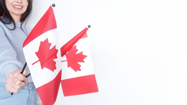 Unrecognized girl student in white blue shirt holding small Canadian flag over gray background, Canada day, holiday, vote, immigration, tax, copy space.