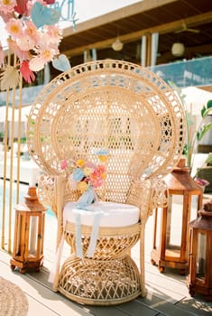 Colorful bridal bouquet stands on a wicker chair near the wedding arch. High quality photo