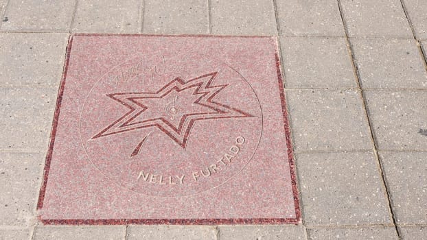 A sidewalk with celebrity handprints and signatures. The concrete has a light gray color, and the handprints and signatures are a dark color. Some of the signatures are difficult to read.