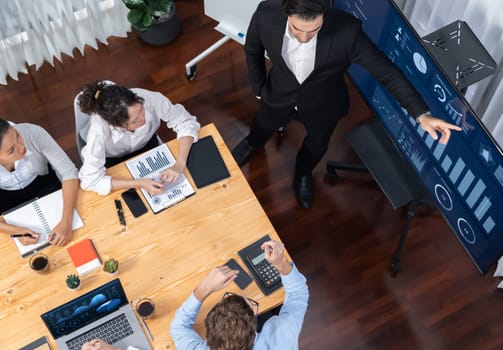 Wide top view of diverse group of business analyst team analyzing financial data report paper on meeting table. Chart and graph dashboard by business intelligence analysis. Meticulous